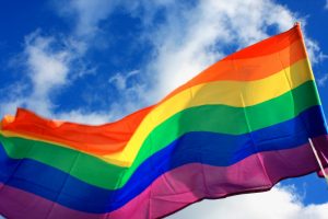 Pride flag raised against sky background