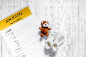 Adoption application near toy on light wooden table 